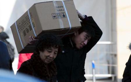 A railway passenger carrying a box walks to the railway station in Beijing, Jan. 30, 2010, the first day of China's Spring Festival travel peak. China on Saturday began its annual mass passenger transportation for the traditional Lunar New Year, with an expected 2.54 billion journeys in the coming 40 days. (Xinhua/Fan Jiashan)