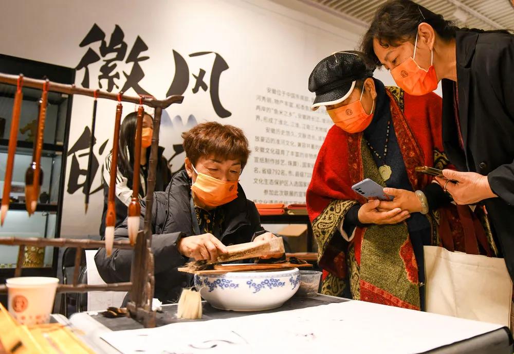 在新疆美术馆展馆内，来自安徽省的非遗传承人吴琼（左）在现场演示毛笔制作。